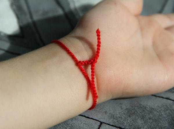 Mengapa benang merah dipakai di tangan 